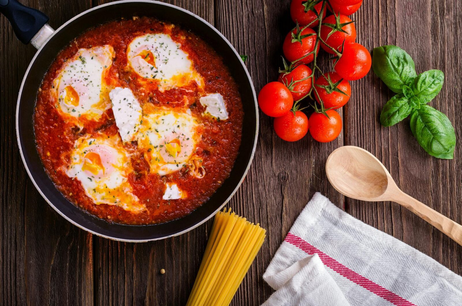 black frying pan with spaghetti sauce near brown wooden ladle and ripe tomatoes 4 Easy Ways to Build Flavor in Home Cooking (Without Overcomplicating Things)