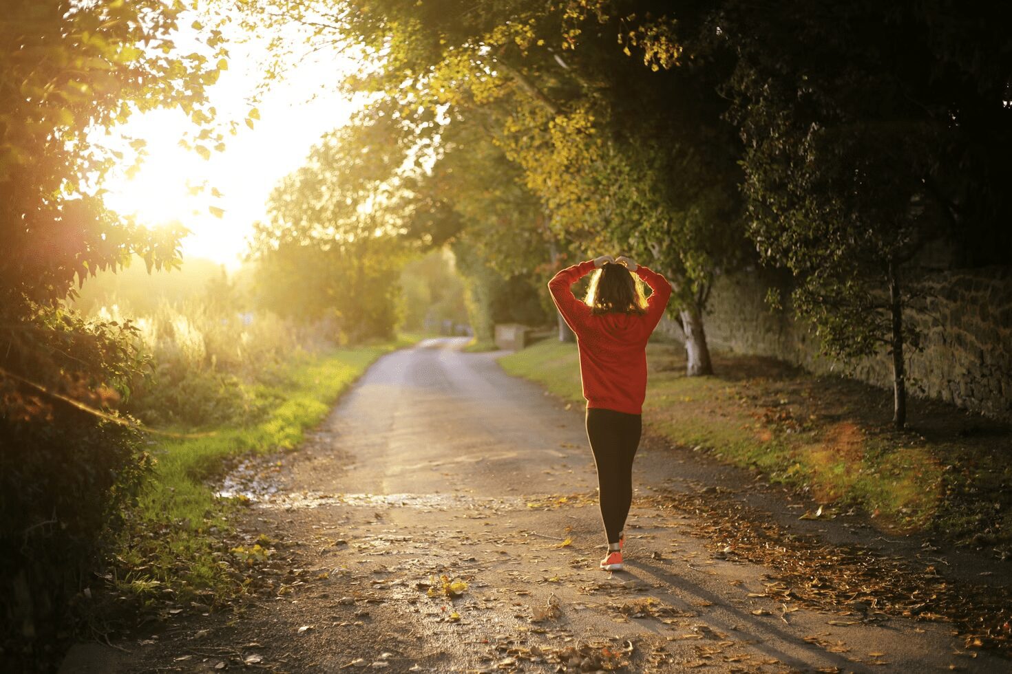 A person in a red sweater walking on a tree-lined pathway during sunset, enjoying the serene atmosphere. Calming Techniques for When Your Thoughts Feel Out of Control