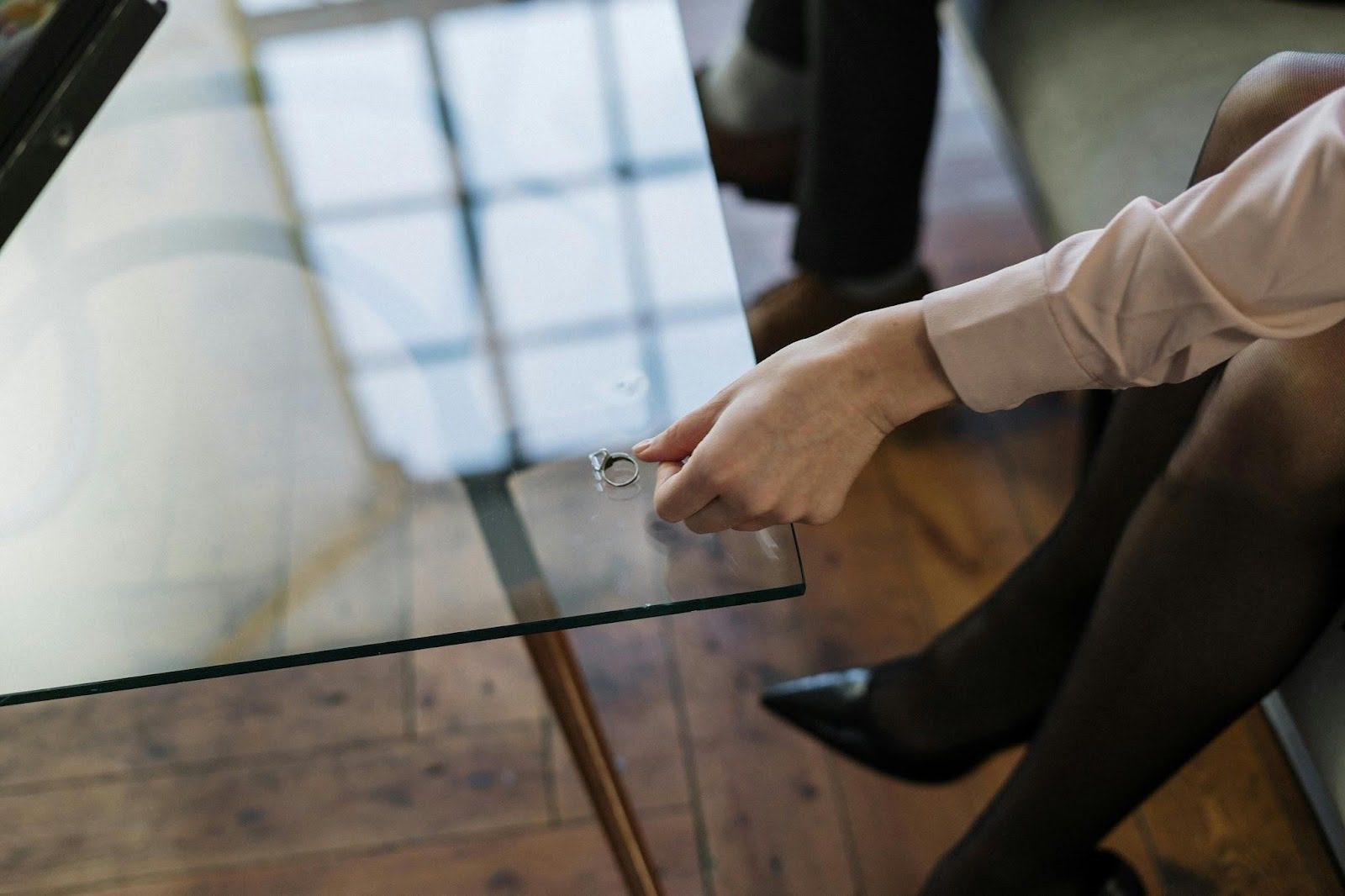 How to Navigate Divorce: Emotional, Legal, and Financial Realities 12 A person placing a ring on a glass table, suggesting themes of contemplation and emotional transitions related to divorce. How to Navigate Divorce: Emotional, Legal, and Financial Realities