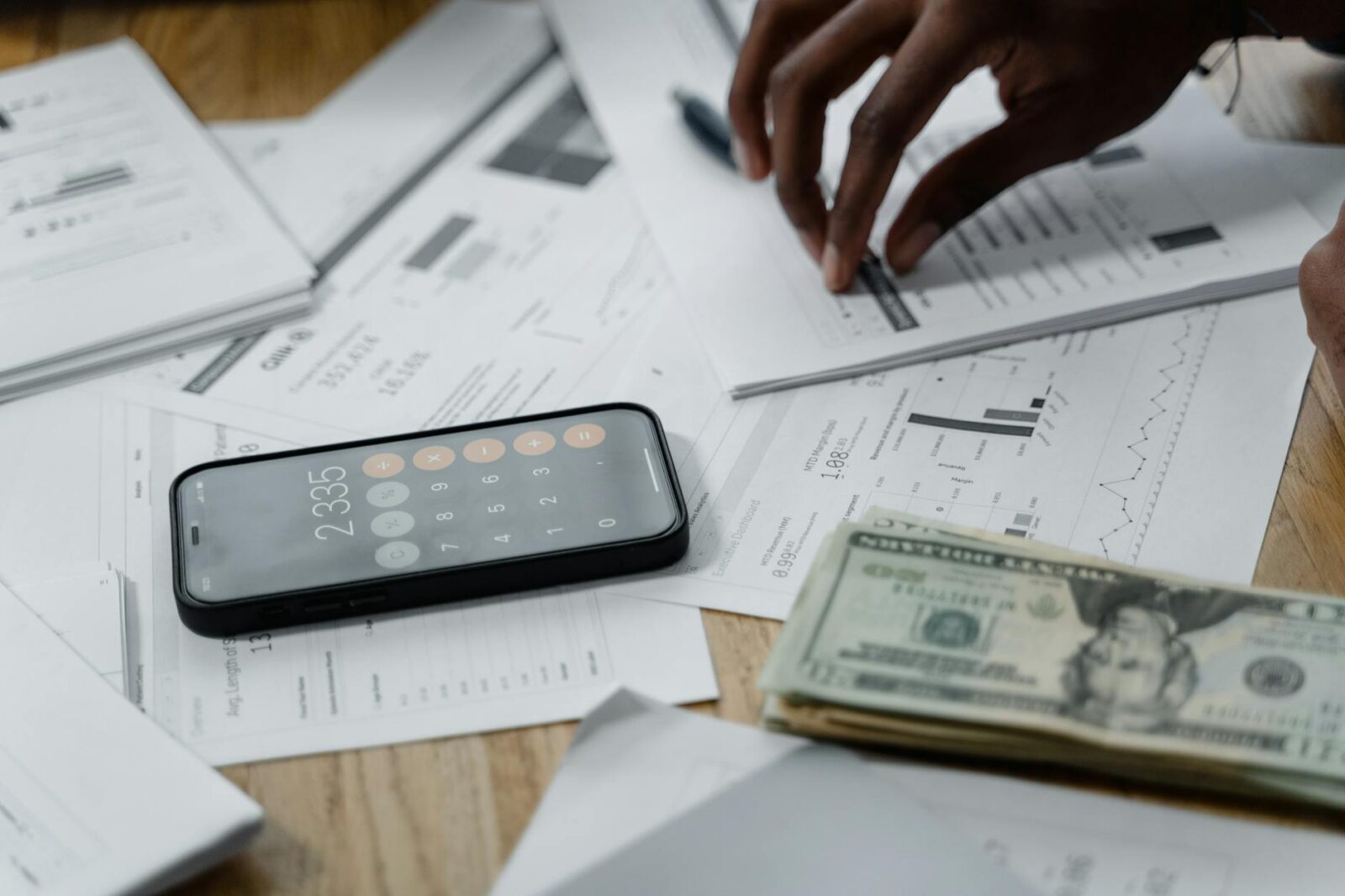 smartphone calculator and dollar bills on papers on table top