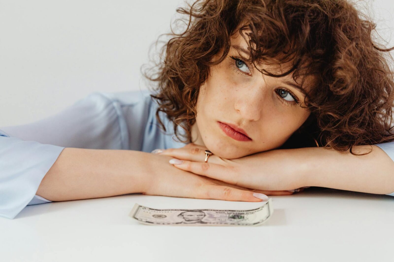 close up shot of a curly haired woman leaning her arms on white surface Stop Suffering in Financial Silence: Practical Steps Toward Stability