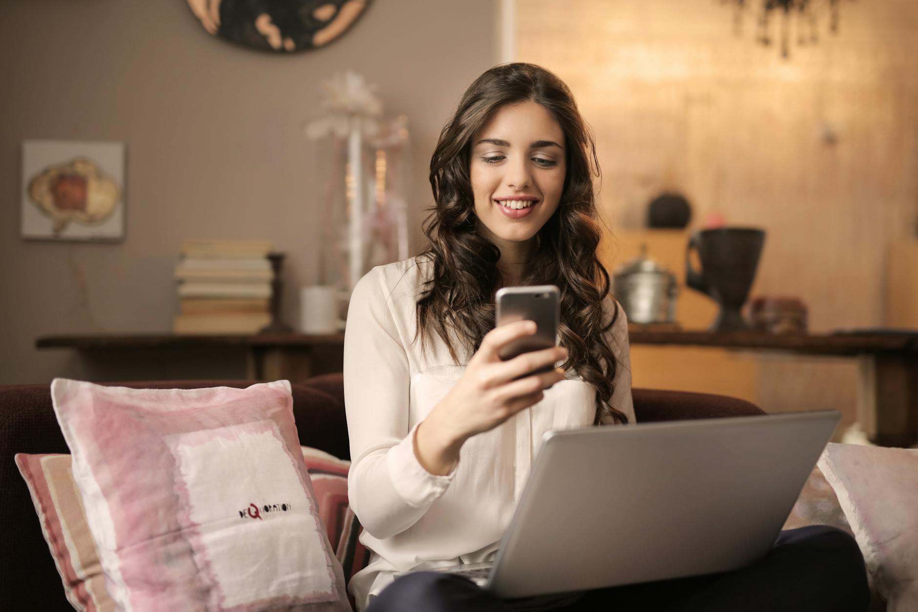 The Sanity-Saving Guide for Online Store Owners 8 woman sitting on sofa while looking at phone with laptop on lap The Sanity-Saving Guide for Online Store Owners